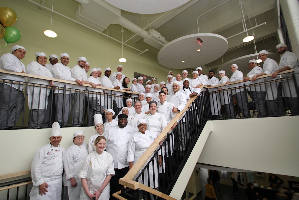 A group of culinary arts students posing on the stairs in the HCC MGM Culinary Arts Institute